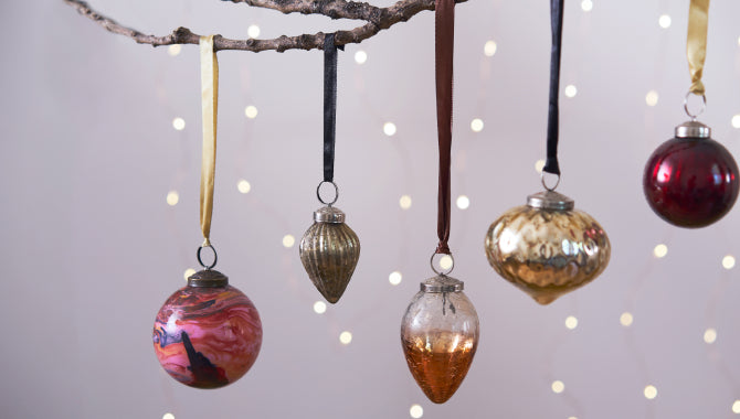 Set of 5 hanging christmas glass baubles hanging from a tree branch on a string