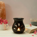 Black ceramic oil burner with a tealight burning in the center