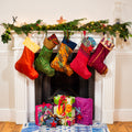 5 sari christmas stockings hanging from a festive mantlepiece with wrapped gifts underneath. Each stocking is handmade using recycled sari fabric and displayed in the colours red, green, orange, light red, and dark red
