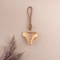 gold heart ornament hanging from a wall on a cotton rope