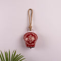 red bell ornament hanging from a wall on a cotton rope